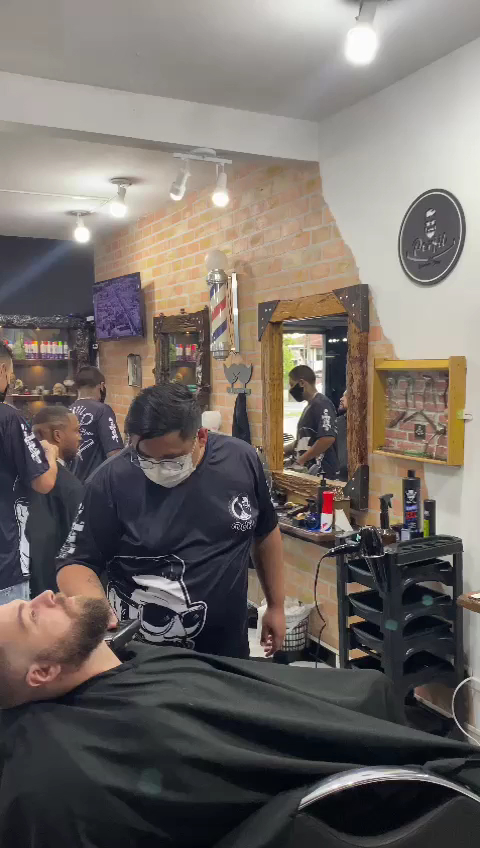 Barbeiro da equipe do Perfil Barber Shop atendendo cliente na cadeira
